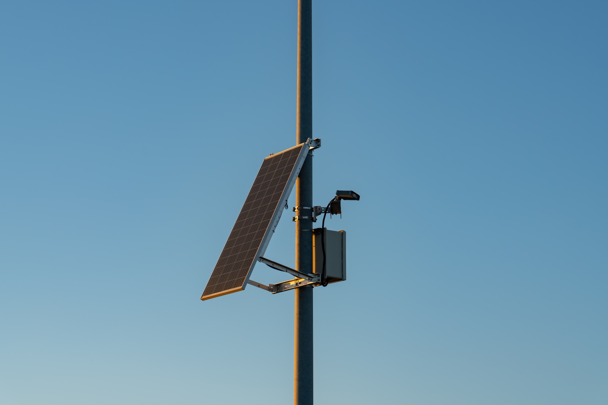A camera and solar panel attached to a streetlight pole.